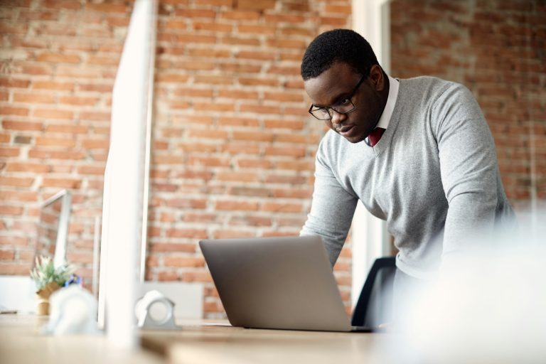 African American businessman reading an e-mail on laptop in the office.