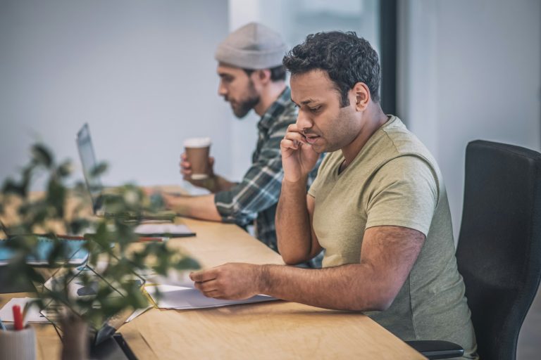 Two guys with laptop and smartphone working in office